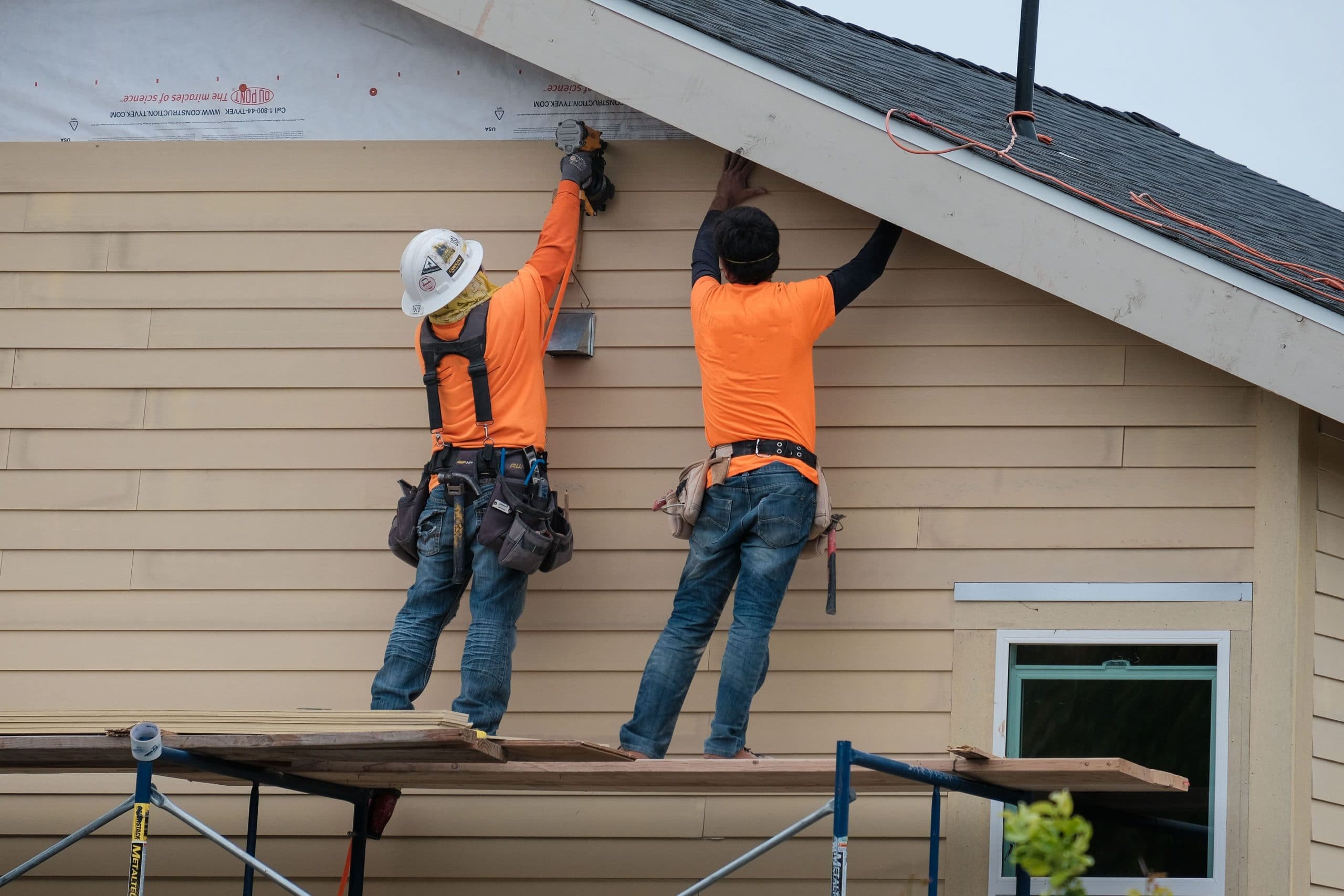 Team of contractors installing siding on a house
